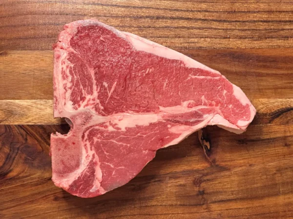 Raw T-bone steak on wooden cutting board
